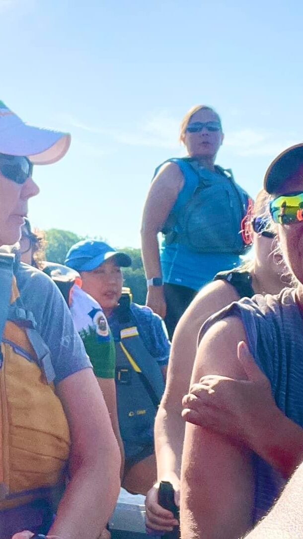 Ginny steering a dragon boat. Sunwashed image. Blue sky in background.